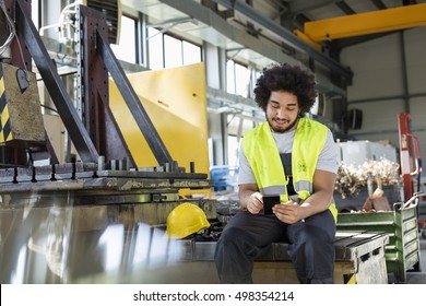 Young Manual Worker Using Mobile Phone In Metal Industry