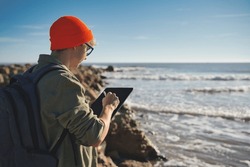 Young Marine Biologist Studying Marine Fauna With An Electronic Tablet On The Seashore. Control Of The Environment.