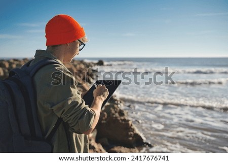 Young marine biologist studying marine fauna with an electronic tablet on the seashore. Control of the environment.