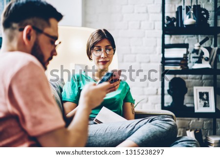 Young marriage ignoring live communication for chatting online with followers from website connected to 4g wireless in stylish home interior, millennial man and woman using smartphone gadgets indoors