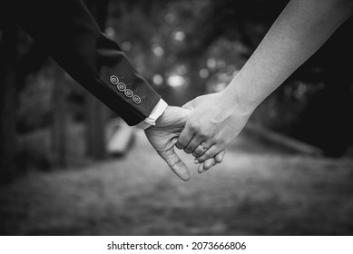 Young married couple, bride and groom, holding hands on the wedding day. Wedding theme with selective focus. Shallow DOF. Matt film effect.