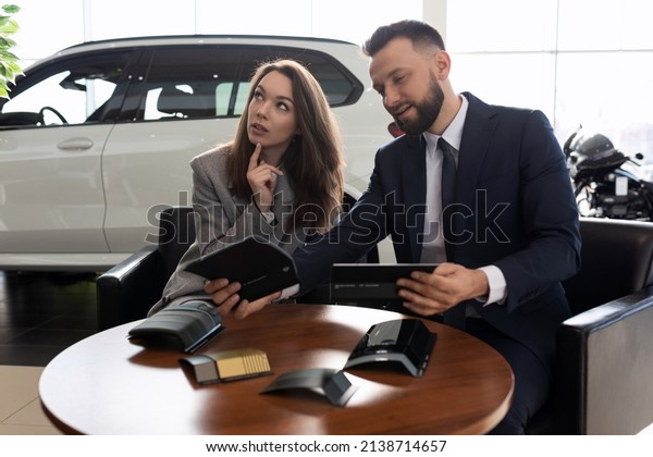 a young married couple\
in a car dealership chooses a car sits with a smile in the trunk of\
a crossover