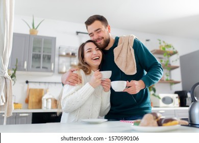 young married couple drinks coffee in the kitchen - Powered by Shutterstock