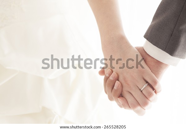 Young\
married couple holding hands, ceremony wedding\
day