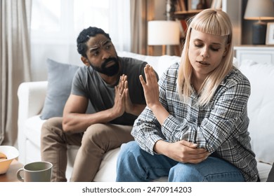 Young married couple husband and wife sitting at home having problems in their marriage and a cold relationship. A boyfriend and a girlfriend roommates have an argument about spending too much money - Powered by Shutterstock