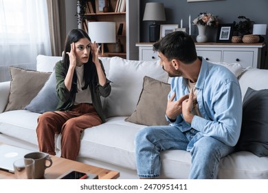 Young married couple husband and wife sitting at home having problems in their marriage and a cold relationship. A boyfriend and a girlfriend roommates have an argument about spending too much money - Powered by Shutterstock