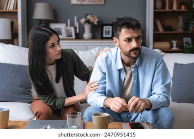 Young married couple husband and wife sitting at home having problems in their marriage and a cold relationship. A boyfriend and a girlfriend roommates have an argument about spending too much money - Powered by Shutterstock