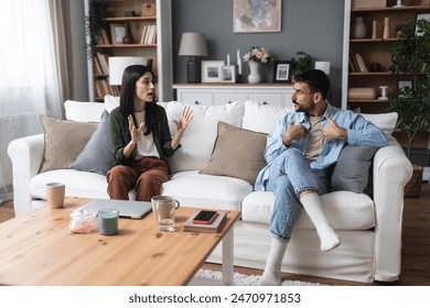 Young married couple husband and wife sitting at home having problems in their marriage and a cold relationship. A boyfriend and a girlfriend roommates have an argument about spending too much money - Powered by Shutterstock