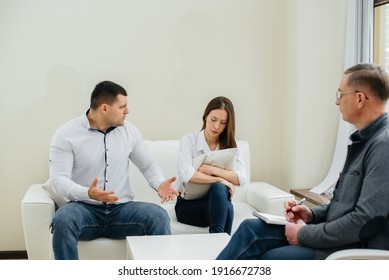A young married couple of men and women talk to a psychologist at a therapy session. Psychology.