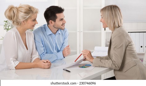 Young Married Couple Sitting With An Adviser At Desk In A Guidance Or Professional Business Meeting Planning Their Provision For One's Old Age.