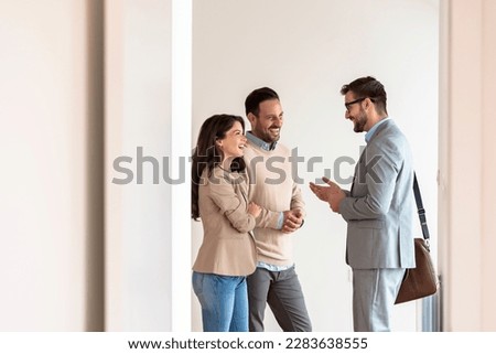 Young married couple talking with a real-estate agent visiting apartment for sale or for rent. Future parents buying an apartment. Real estate concept. A new beginning