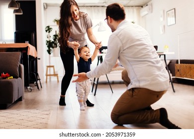 Young married couple teaching their son to learn the first baby steps in their home - Shutterstock ID 2053971359