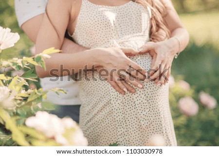 Young married couple waiting for the birth of a child. The future father touches the pregnant belly of his wife