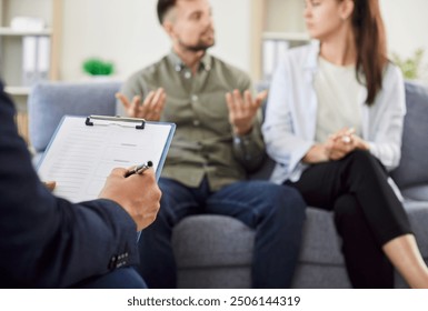 Young married upset couple man and woman sitting on sofa in counselor's office during family therapy session with male psychologist trying to find solution. Effective marital therapy concept. - Powered by Shutterstock