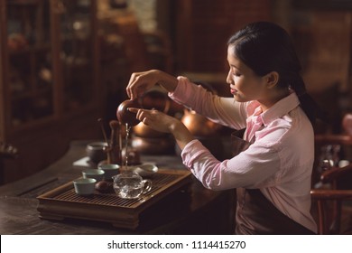 Young master pouring tea from a teapot indoors