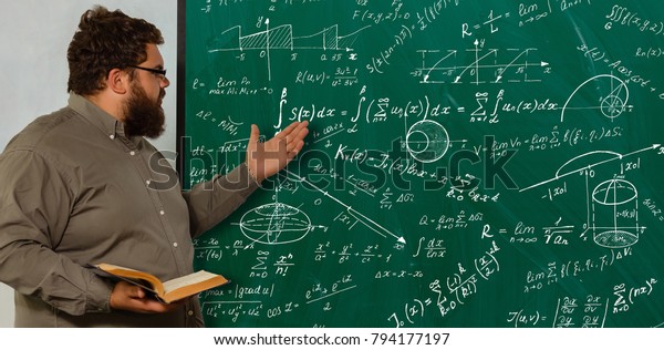数式を使って緑の黒板の近くに立つ間に難しい方程式を解く若い数学の天才 の写真素材 今すぐ編集