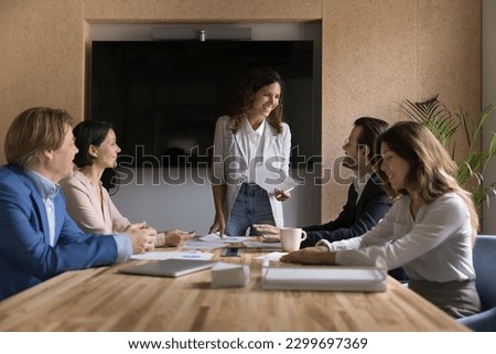 Young and mature businesspeople gather in boardroom to discuss deal. Pretty Hispanic businesswoman, company boss, trainer leads formal meeting, corporate training for staff, take part in negotiations 商業照片 © 