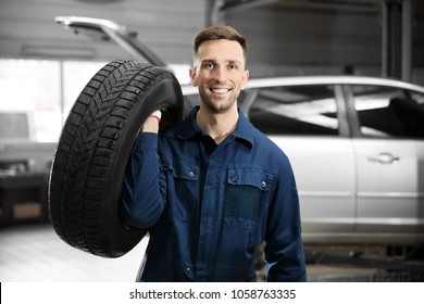 Young Mechanic With Car Tire In Service Center