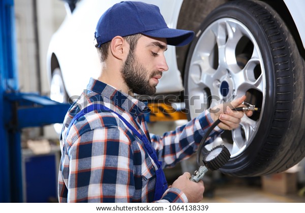 Young\
mechanic checking tire pressure in service\
center