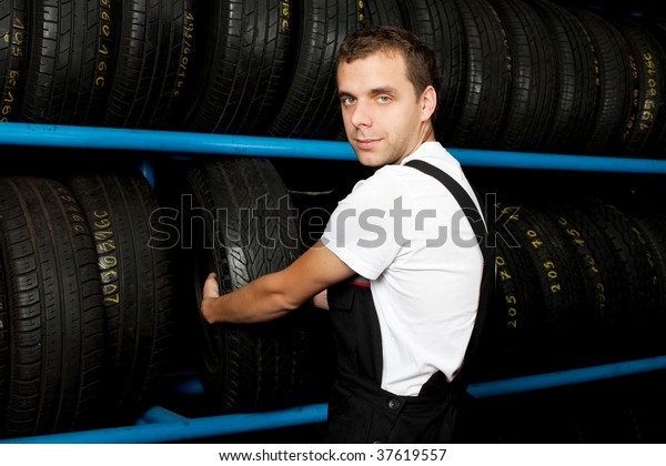Young mechanic\
choosing tire in tire\
store