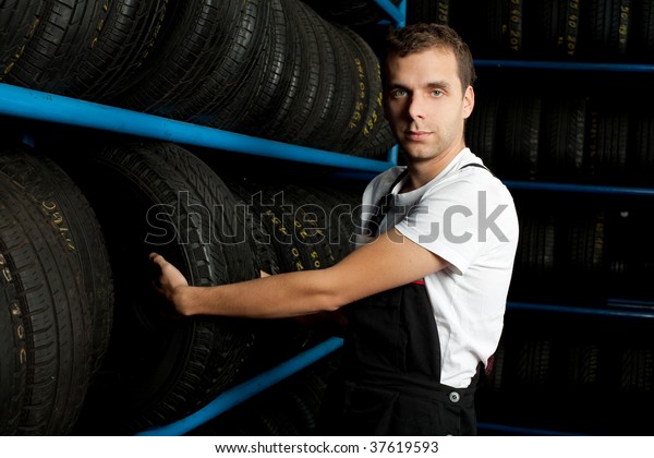 Young mechanic\
choosing tire in tire\
store