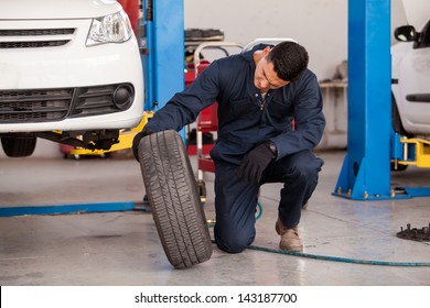 Young mechanic inspecting a car tire at an auto shop