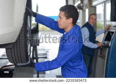 young mechanic inspecting the car wheel
