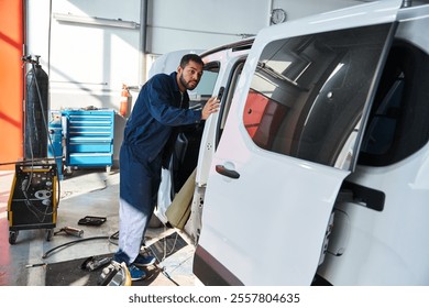 Young mechanic inspects a van while sunlight streams through the workshop windows