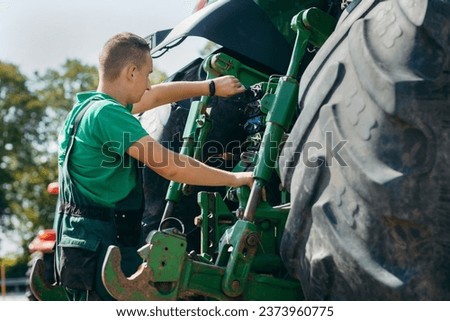 Young mechanic repair tractor outdoor