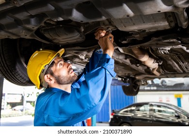 Young Mechanic Repairing Undercarriage Of Car In Auto Repair Shop.