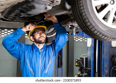 Young Mechanic Repairing Undercarriage Of Car In Auto Repair Shop.