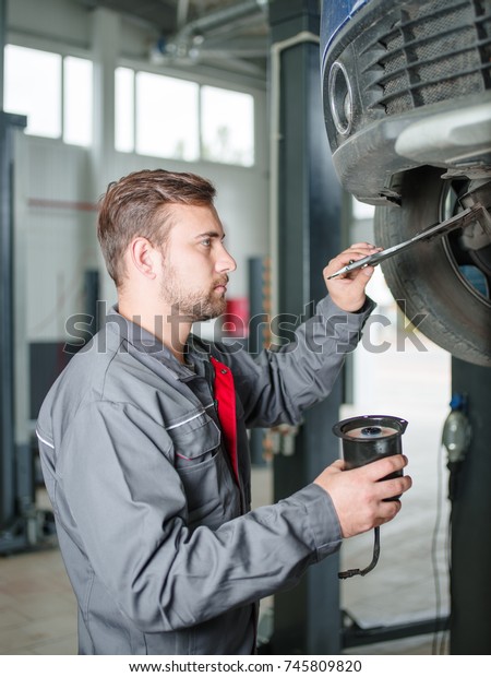 Young\
mechanic with a tool in hand replacing a car\
tire