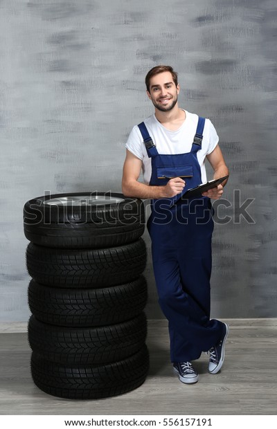 Young mechanic in uniform with a clipboard, on\
gray background