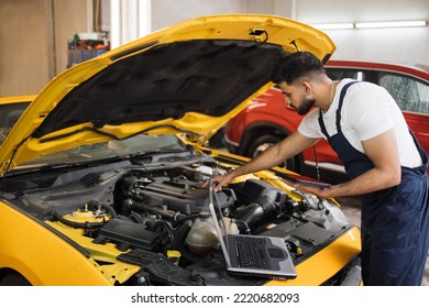 Young Mechanic Using Tablet Computer, Recording Automobile Engine Checks Collect Detailed Information During His Work On Car Workshop. Service Maintenance During Engine Repair.