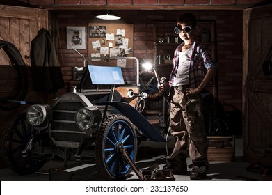 Young Mechanic With A Welder In A Retro Car In The Garage At Night