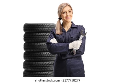 Young Mechanic Woman Holding A Wrench In Front Of A Pile Of Tires Isolated On White Background