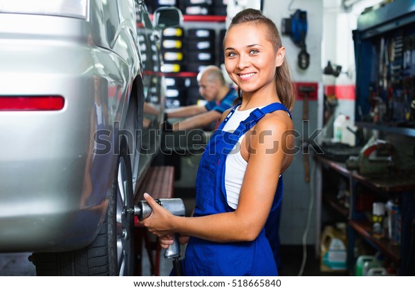 Young mechanic woman working on wheel\
equilibrium control machinery in car\
service