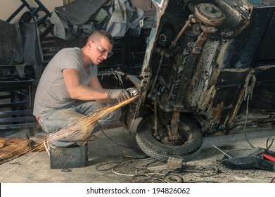 Young Mechanical Worker Repairing An Old Vintage Car Body In Messy Garage