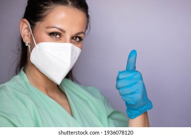 Young Medical Professional, Nurse With Protective Mask And Smiling Eyes, Showing Thumbs Up. Isolated On Gray Background