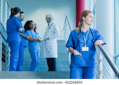 Young medical student with a stethoscope standing on stairs, in the background group of students talking with a doctor in uniform - Powered by Shutterstock