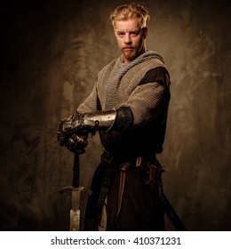 Young Medieval Knight Posing On Dark Background. 