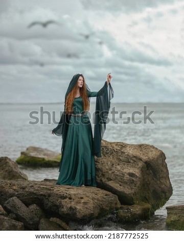 Young medieval maiden on stones by the stormy sea