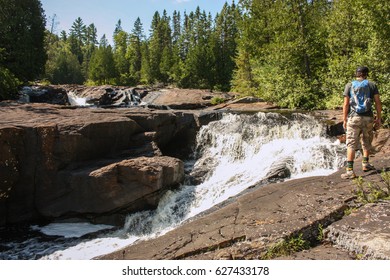 young men with backpack looking at a waterfall