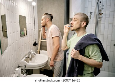 Young Men Brushing Teeth In Front Of Mirrors In Dorm Bathroom In The Morning