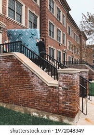 Young Men Carrying Mattress Into Townhouse Apartment