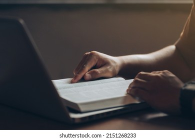 Young men concentrate on reading books with a laptop computer on the desk at home.Studying the Word Of God. bible study Concept - Powered by Shutterstock