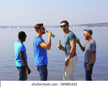 Young Men Drinking Beer On The Riverside