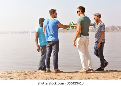 Young Men Drinking Beer On The Riverside