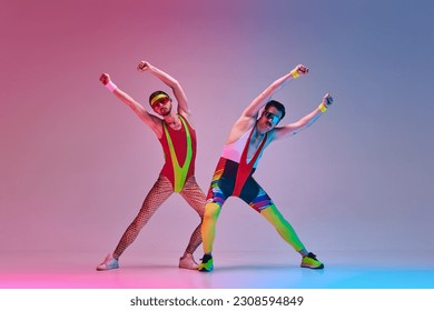 Young men, fitness coach in colorful sportswear stretching, training against gradient blue pink studio background in neon light. Concept of sportive and active lifestyle, humor, retro style. Ad