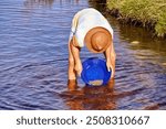 A young men with a hat gold panning
panning in a mountain stream